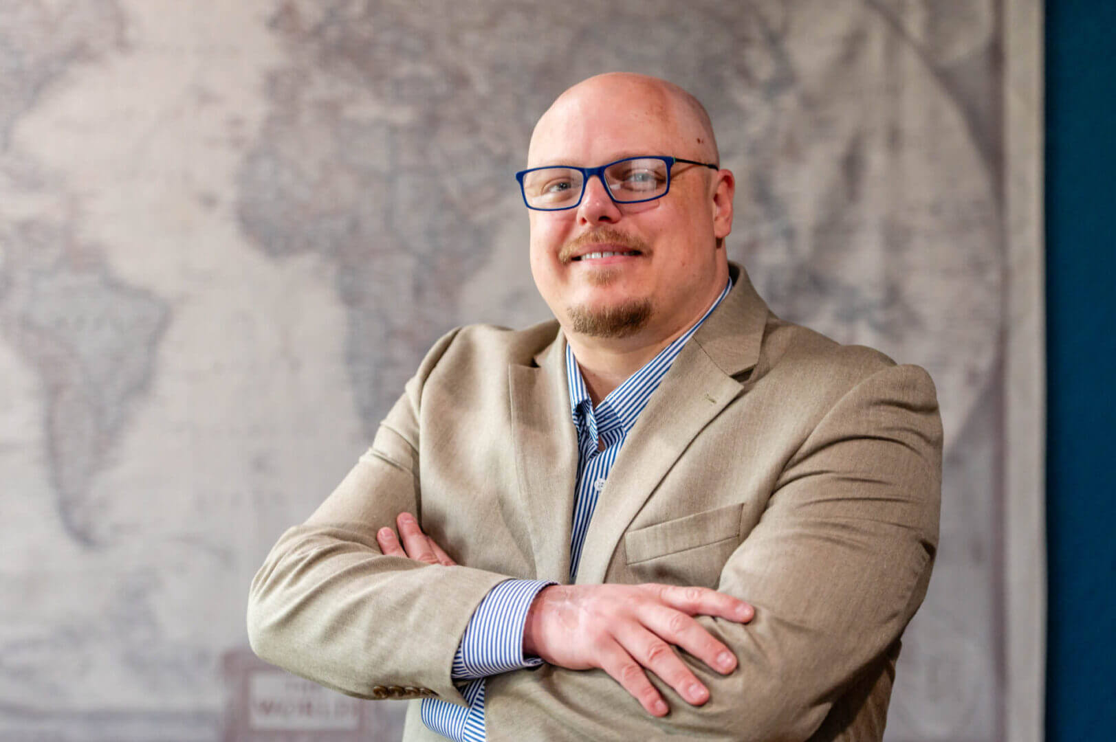 Man in glasses with arms crossed, smiling.